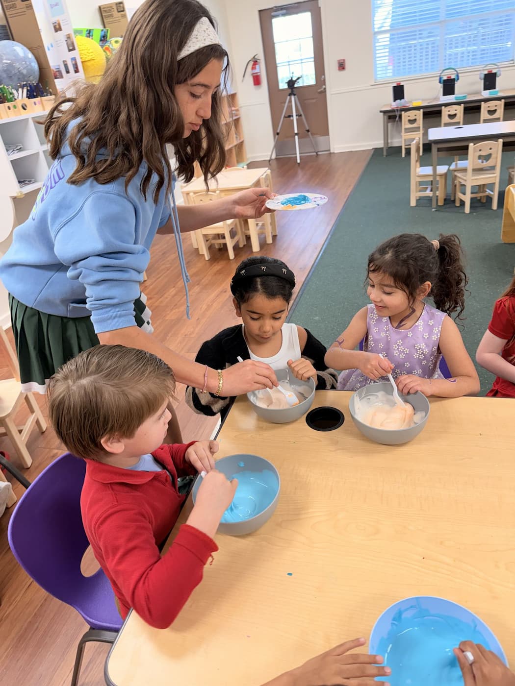 Palm Grove Montessori teacher guiding children through hands-on sensory mixing activity in Plano TX classroom