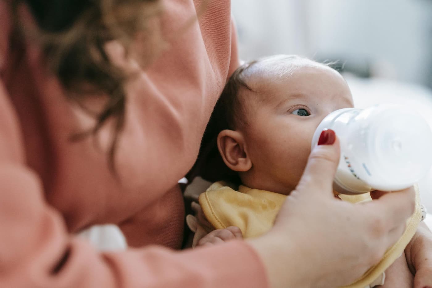 Infant care Plano TX caregiver bottle-feeding baby in a calm classroom